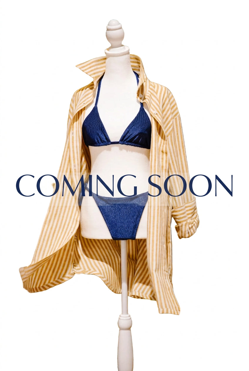 A mannequin torso wearing a navy blue bikini with a cream and tan striped button-up shirt dress