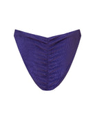 A close-up of a rib textured, ruched fabric cheeky bikini bottom in a navy blue color, with a mid-rise.