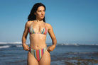 Woman wearing an adjustable triangle string bikini top and a high-waisted cheeky bikini in a vertical bright colored stripe.
